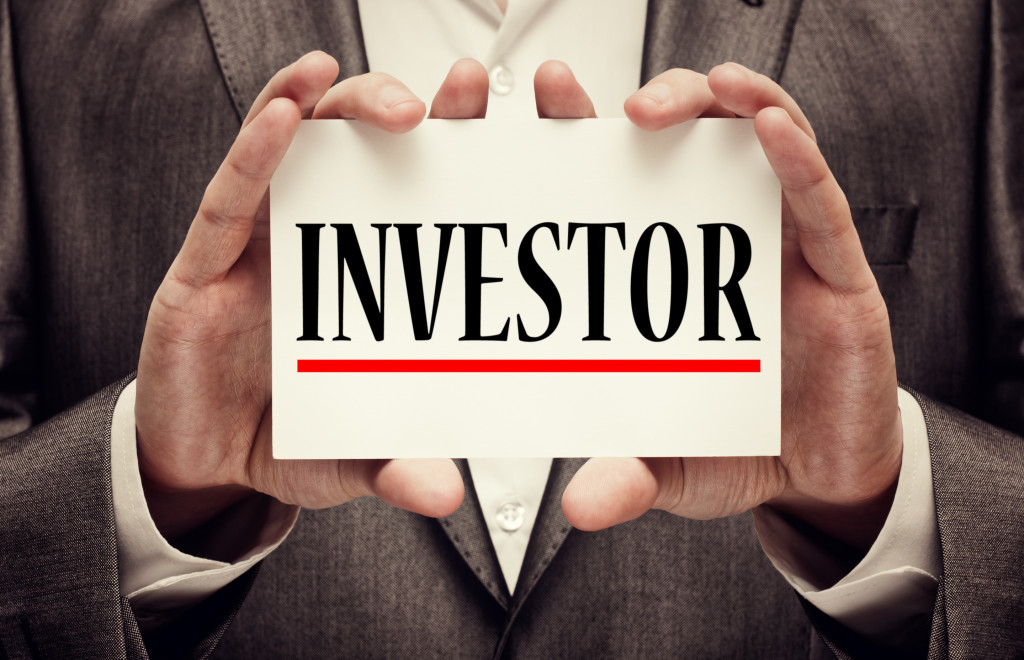 suited man holding the word investor underlined in red